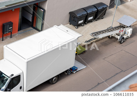 Mover service lifting ladder cargo crane platform vehicle van parked at city street. Retractable furniture elevator machine car pickup truck rental company for relocation and house moving delivery 106611035