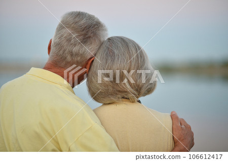 Mature couple on a summer evening watching the lake 106612417