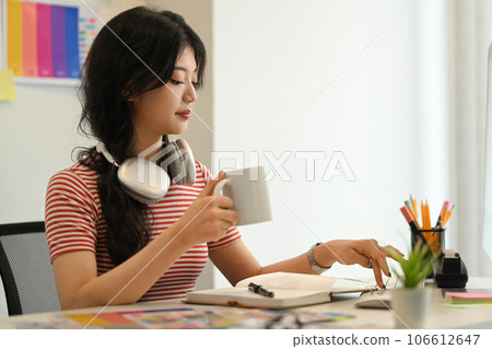 Young stylish woman with headphone working on new design project at graphic studio Young stylish woman with headphone working on new design project at graphic studio 106612647