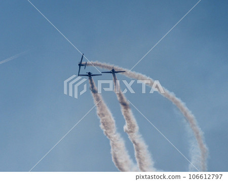 Three aircraft perform aerobatics, behind them stretches clearly visible against the blue sky inversion trail indicating the flight path. Three aircraft perform aerobatics, behind them stretches clearly visible against the blue sky inversion trail indicating the flight path. 106612797