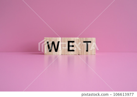 Wooden blocks form the text "WET" against a pink background. Wooden blocks form the text "WET" against a pink background. 106613977