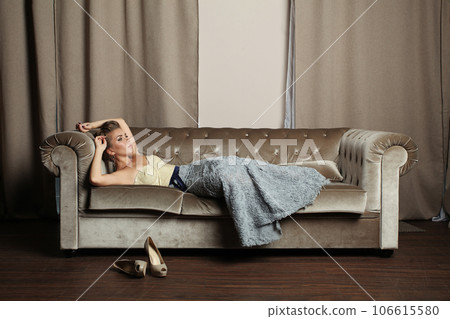 Beautiful fashionable woman in luxurious dress resting on sofa indoor, fashion portrait Beautiful fashionable woman in luxurious dress resting on sofa indoor, fashion portrait 106615580