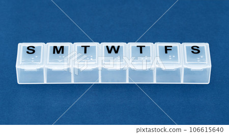 Empty long plastic weekly pillbox on blue background. 106615640