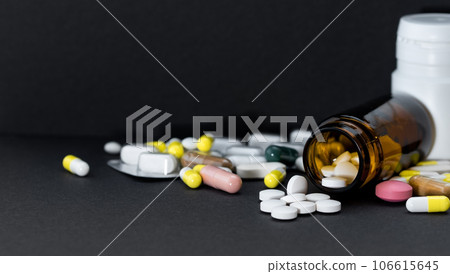 Pill bottle with spilling varied medicine over black. Pill bottle with spilling varied medicine over black. 106615645