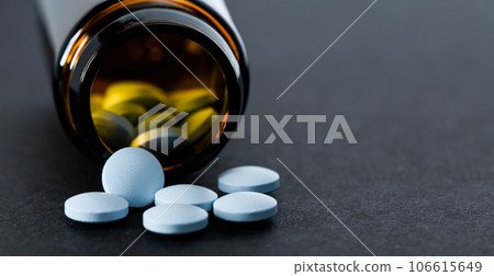 Pill bottle spilling out blue pills, copy space, space for text. 106615649
