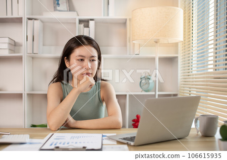 Woman using laptop to work or do homework at home with smiling face in her office, Creating happiness at work with a smile, Live performance or vdo call with laptop, Work from home. 106615935