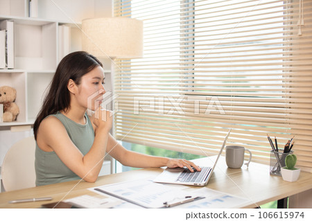 Woman using laptop to work or do homework at home with smiling face in her office, Creating happiness at work with a smile, Live performance or vdo call with laptop, Work from home. 106615974