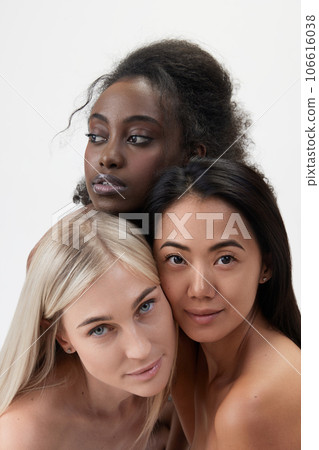 Portrait of beautiful young african, caucasian and asian women with well-kept skin looking at camera against white background 106616038