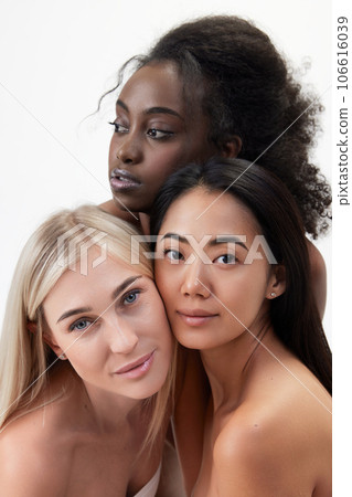 Portrait of beautiful young african, caucasian and asian women with well-kept skin looking at camera against white background 106616039