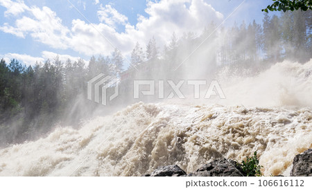 powerful stream during an idle discharge of water against the background of a building of a small hydroelectric power station powerful stream during an idle discharge of water against the background of a building of a small hydroelectric power station 106616112