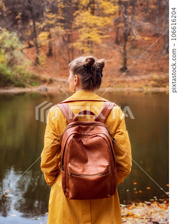 Woman Standing Backwards in Autumn Forest with Lake 106616204