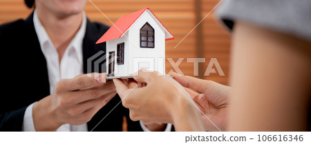 Young realtor man real estate giving house model to hands customer while agreement. 106616346