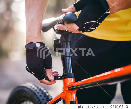Rider adjusting seat height on bicycle 106616740