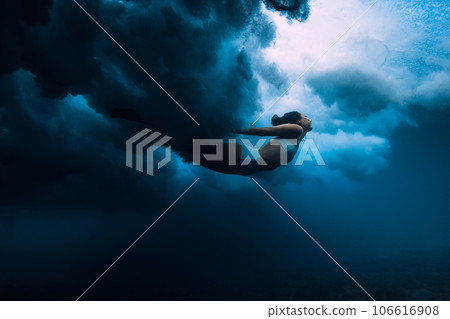 Woman dive under wave. Duck dive under crashing barrel wave in transparent ocean Woman dive under wave. Duck dive under crashing barrel wave in transparent ocean 106616908