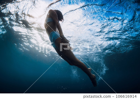 Woman underwater swim with ocean wave and sun rays. Woman underwater swim with ocean wave and sun rays. 106616914