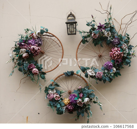 Decoration urban art object from bicycle wheels and flowers on wall Decoration urban art object from bicycle wheels and flowers on wall 106617568