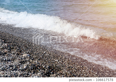 Bank of pebbles with the sea and beach in the background 106617578