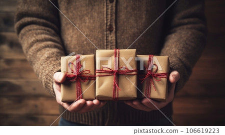 New Year and Christmas gifts, and boxes in the hands of an elderly man on a wooden background.  106619223