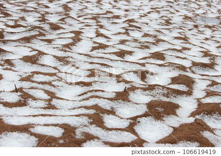 Snow on a sandy beach, undulating sand, summer. Disturbance of the earth's climate, ecological disaster 106619419