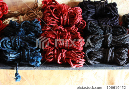 Skeins of 6mm diameter jute rope for Japanese bondage and shibari. Blue, red, black and undyed ropes at the bdsm fair at the shibari festival. Skein of professional knitting. 106619452