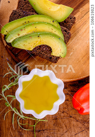 Olive oil, tomato, bread with avocado on wood cutting board. Olive oil, tomato, bread with avocado on wood cutting board. 106619823