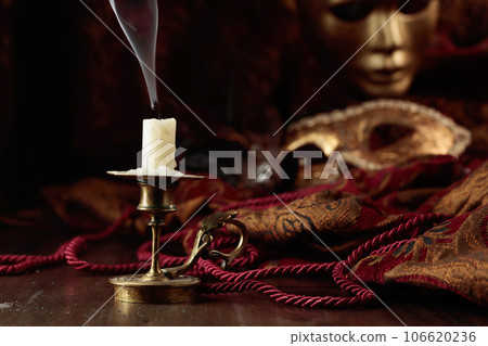 Still life with an extinguished candle and carnival masks. 106620236