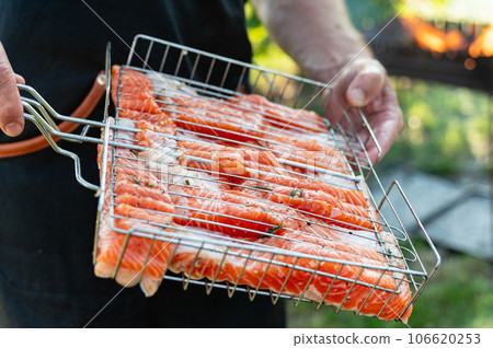 Cooking Raw salmon fillet steak on grill with herbs. 106620253