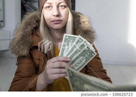 A man in a yellow sweater and jacket with documents in his hands and money 106620723