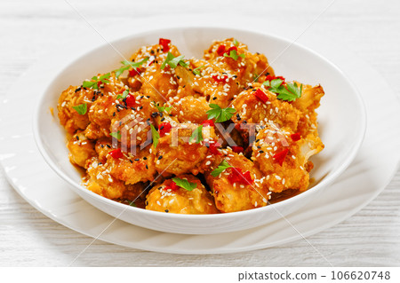 crispy orange cauliflower florets in white bowl 106620748
