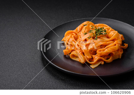 Delicious fresh pasta with pesto sauce, salt, spices and herbs on a ceramic plate 106620906