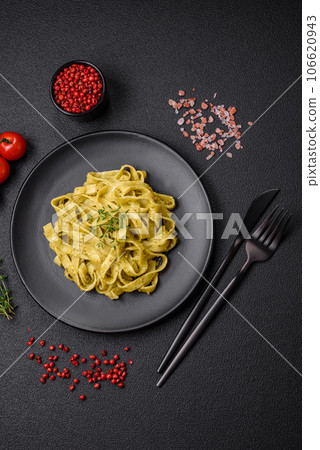 Delicious fresh pasta with pesto sauce, salt, spices and herbs on a ceramic plate Delicious fresh pasta with pesto sauce, salt, spices and herbs on a ceramic plate 106620943