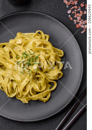 Delicious fresh pasta with pesto sauce, salt, spices and herbs on a ceramic plate Delicious fresh pasta with pesto sauce, salt, spices and herbs on a ceramic plate 106620945
