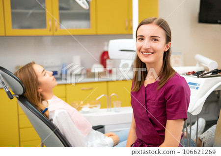 Female dentist looks at the camera while patient waiting for the procedure sitting on the medical chair 106621269