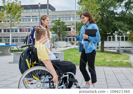 Female teacher and children, boy in wheelchair and girl talking outdoor Female teacher and children, boy in wheelchair and girl talking outdoor 106621360