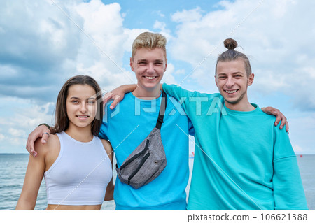 Portrait of cheerful teenage friends hugging on beach Portrait of cheerful teenage friends hugging on beach 106621388