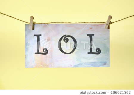 LOL. lettering on colored paper hanging in front of a yellow background with a rope and clothespins 106621562