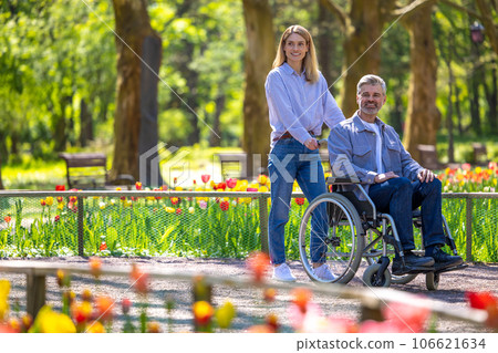 Man in wheelchair with loving woman in park. 106621634