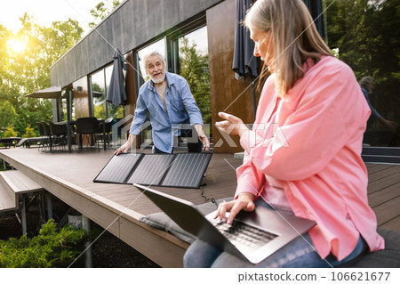 Woman and man working on laptop using solar panel. 106621677