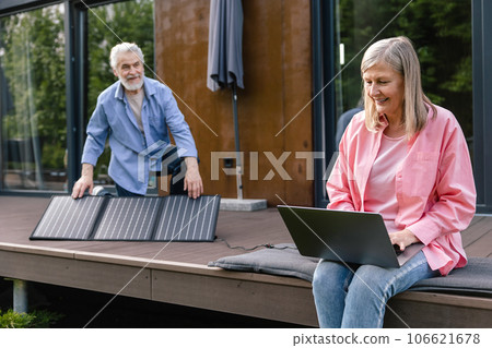 Mature couple using laptop in front of solar panels. Mature couple using laptop in front of solar panels. 106621678