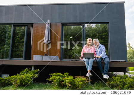 Woman and man working on laptop using solar panel. 106621679
