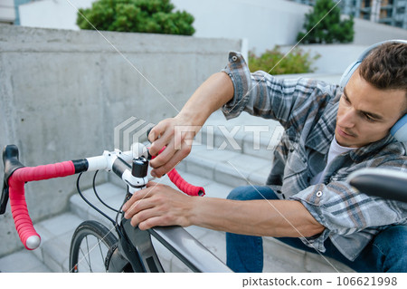 Smiling young man fixing a problem with the bike Smiling young man fixing a problem with the bike 106621998