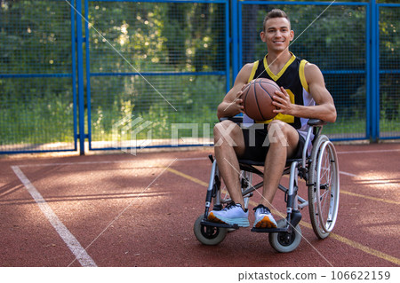 Wheelchair basketball player holding, disability, outdoor basketball court. 106622159