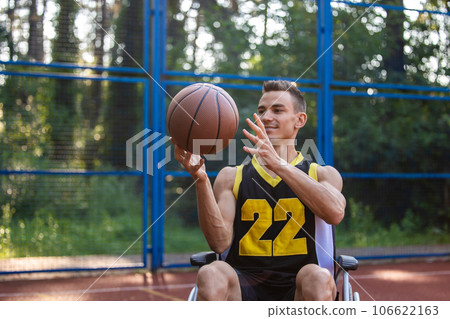 Young man in wheelchair playing basketball outdoor. 106622163
