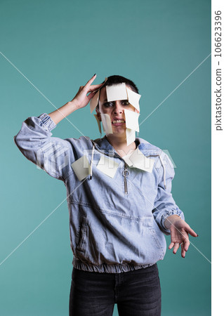 Tired exhausted woman with colorful sticky notes all over her body, having the duty to remember work details. Frustrated overworked female posing in studio standing over isolated background 106623396