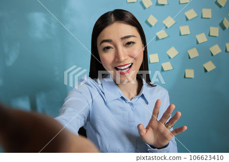 Businesswoman on video call with mobile phone talking in a friendly way with friends during break time. Female office employee using mobile device for remote communication. Businesswoman on video call with mobile phone talking in a friendly way with friends during break time. Female office employee using mobile device for remote communication. 106623410