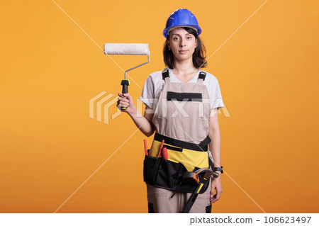 Contractor painter painting walls with roller brush tool doing interior renovation, working on home improvement. Professional construction worker holding paintbrush and roll to redecorate. 106623497