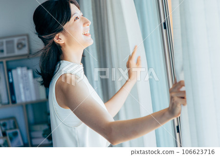 A woman who opens the curtains and bathes in the morning sun A woman who opens the curtains and bathes in the morning sun 106623716