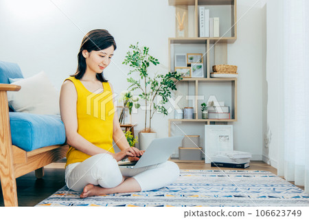 A woman watching a computer in a room 106623749