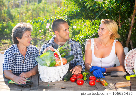 Happy family talking at wooden table in summer home garden Happy family talking at wooden table in summer home garden 106625455