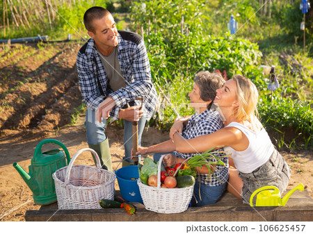 Cheerful elderly woman talking to adult children in home garden Cheerful elderly woman talking to adult children in home garden 106625457